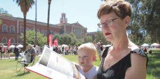 Woman and child enjoying a book on a park bench at the Tucson Festival of Books, embodying the joy of shared reading in a community setting.