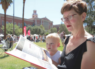 Woman and child enjoying a book on a park bench at the Tucson Festival of Books, embodying the joy of shared reading in a community setting.