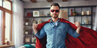 A REALTOR® dressed in a business suit and superhero cape, striking a powerful pose against a cityscape backdrop, representing the 'Prequalify for the Refi' program.